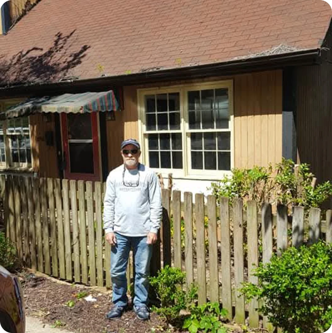 Individual by wooden fence and house